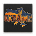 Black fridge magnet featuring UKRAINE collage wordmark on blue and gold map with cultural portraits, embroidery and sunflowers