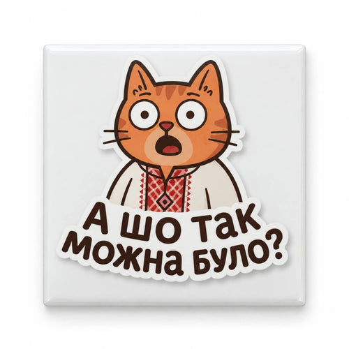 White square magnet showing surprised orange cartoon cat in embroidered shirt and Ukrainian text А шо так можна було?
